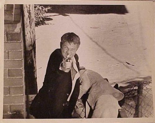 Steve McQueen (as Doc McCoy) fires gun whilst shielding 
Ali MacGraw (as Carol McCoy) from danger.